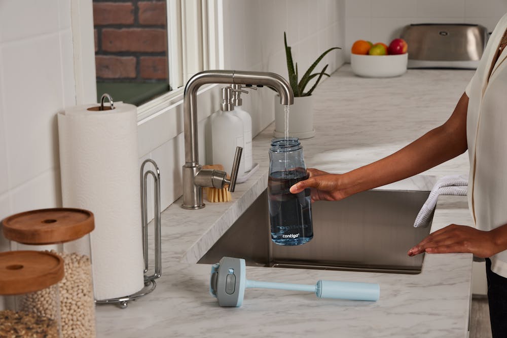 Person filling water bottle at a kitchen sink